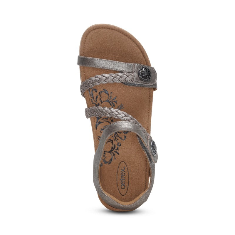 Aetrex Jillian casual sandal in metallic silver with braided straps on a tan footbed.